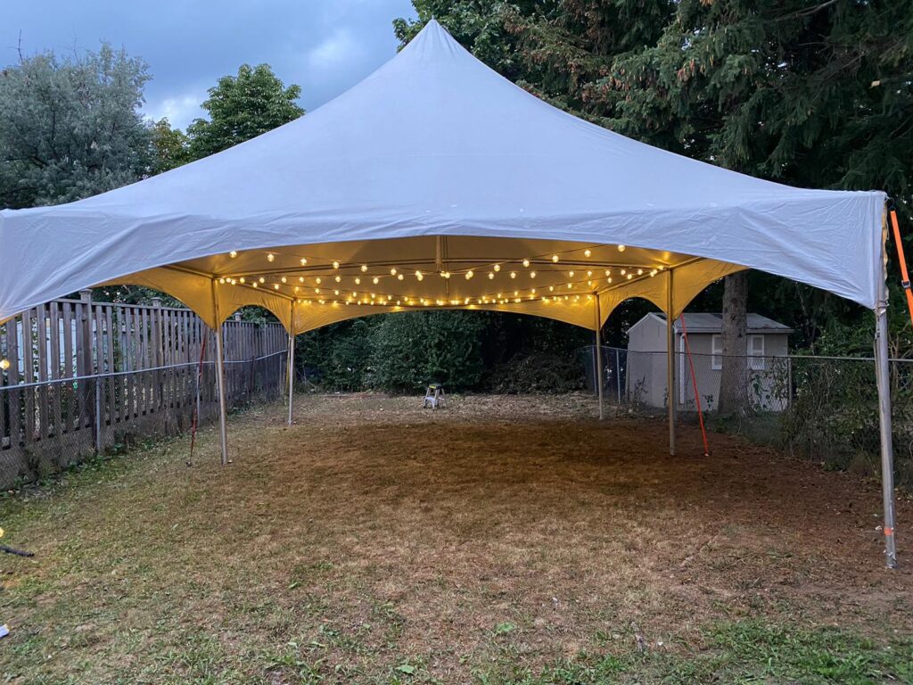 20x30 high peak marquee tent with globe lights in a backyard