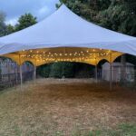 20x30 high peak marquee tent with globe lights in a backyard