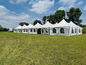 Large high-peak marquee tent rental with cathedral windows set up on the grass field at Crusaders Rugby Club, Oakville, ON.
